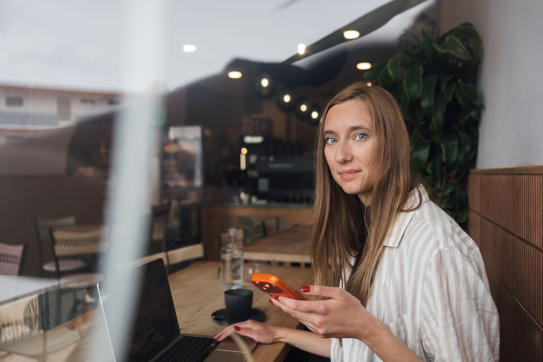 Corinna Reupke im Café mit Smartphone in der Hand