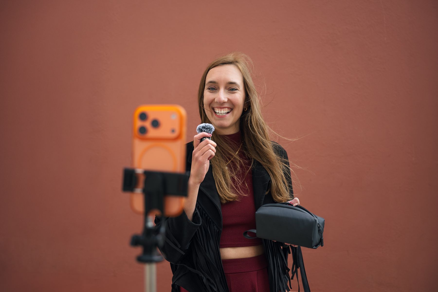 Corinna Reupke filmt sich vor einer terrakottafarbenen Wand mit Smartphone auf Stativ